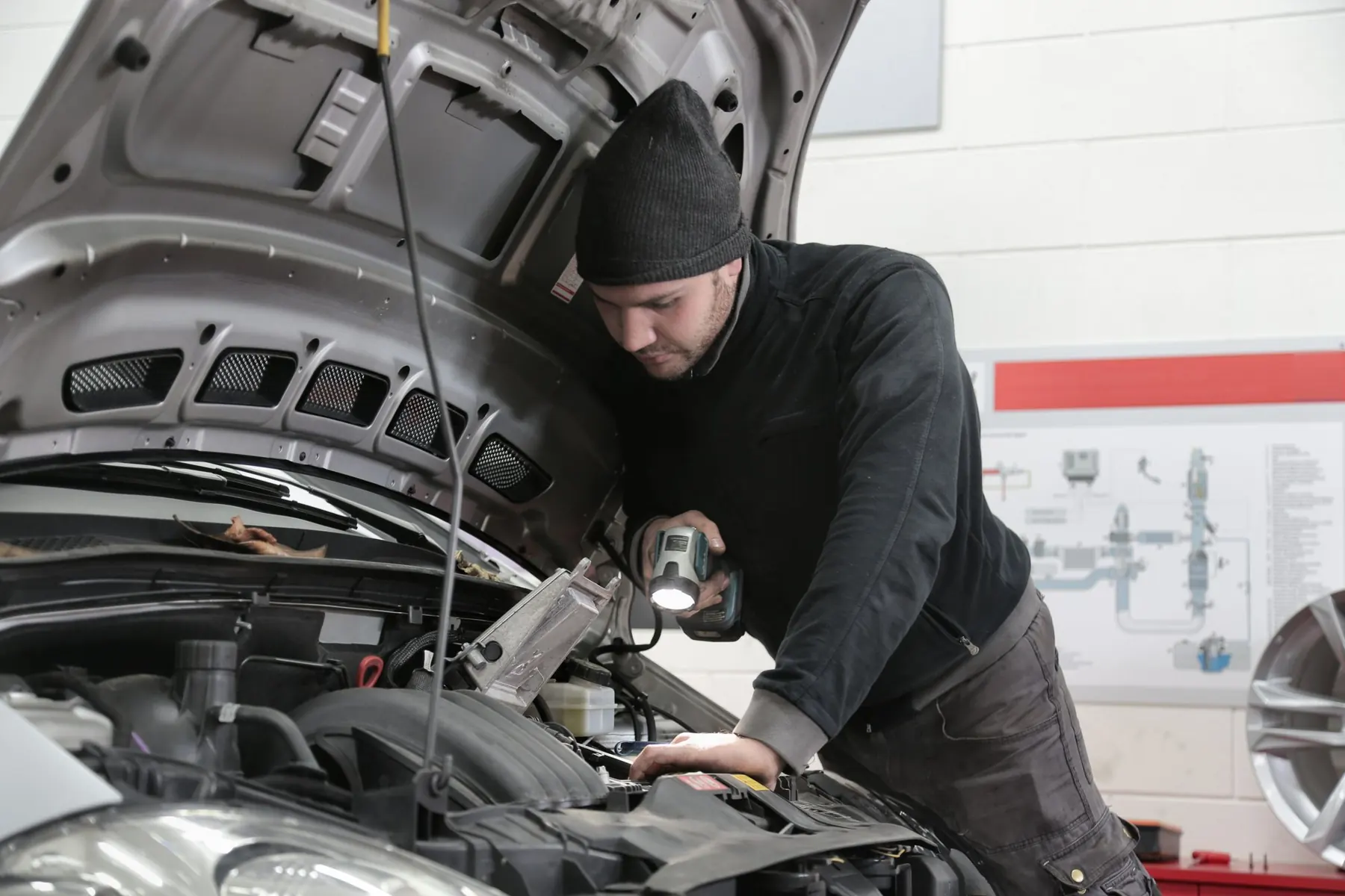 Mecânico inspecionando o motor com uma lanterna